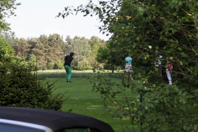 Golfer beim Abschlag auf grüner Wiese